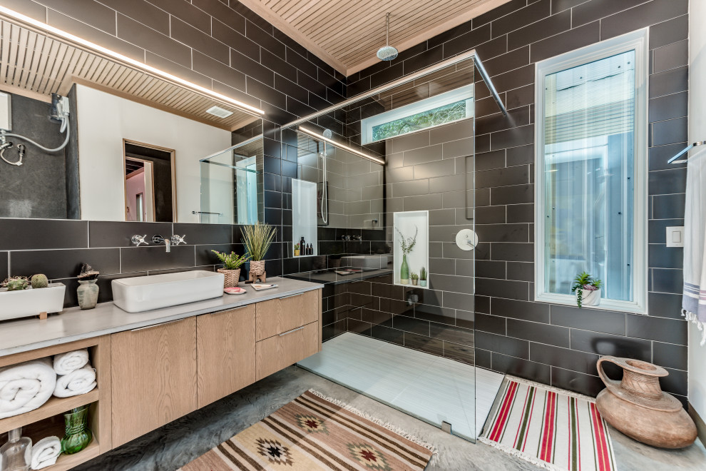 Inspiration for a mid-sized eclectic master bathroom in Houston with flat-panel cabinets, light wood cabinets, a curbless shower, black tile, porcelain tile, white walls, concrete floors, a vessel sink, concrete benchtops, grey floor, an open shower, grey benchtops, a single vanity, a floating vanity and wood.
