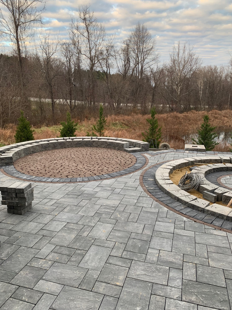 Design ideas for an expansive back patio in DC Metro with a fire feature, natural stone paving and a pergola.