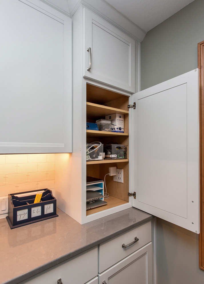 Example of a large transitional u-shaped medium tone wood floor and brown floor eat-in kitchen design with an undermount sink, recessed-panel cabinets, white cabinets, quartz countertops, white backsplash, ceramic backsplash, stainless steel appliances and an island