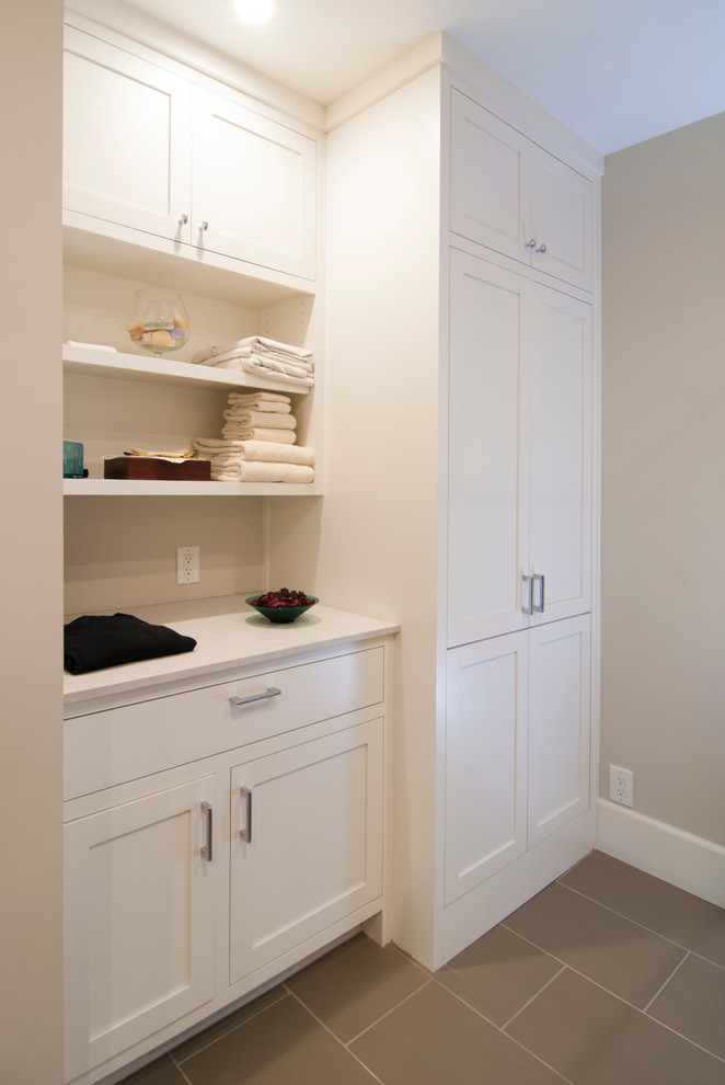 Inspiration for a small traditional galley utility room in San Francisco with shaker cabinets, white cabinets, quartz benchtops, ceramic floors, beige walls and a concealed washer and dryer.