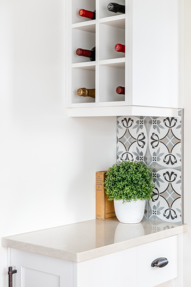 Kitchen pantry - mid-sized transitional l-shaped medium tone wood floor and brown floor kitchen pantry idea with an undermount sink, shaker cabinets, white cabinets, quartzite countertops, gray backsplash, porcelain backsplash, stainless steel appliances, an island and white countertops
