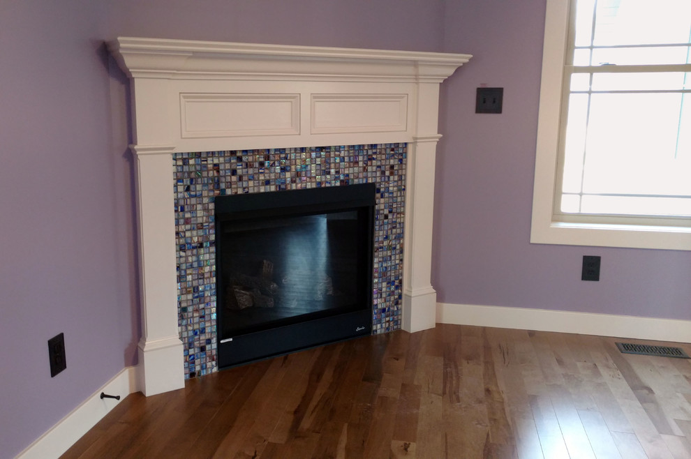 Design ideas for a mid-sized arts and crafts family room in Manchester with purple walls, medium hardwood floors, a corner fireplace, a tile fireplace surround and brown floor.