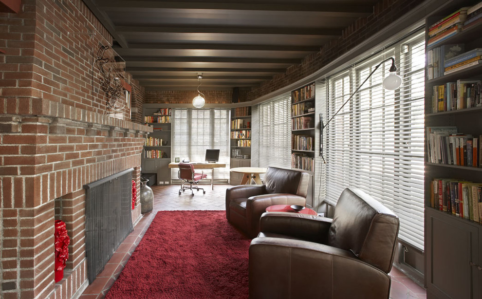 Inspiration for a mid-sized industrial open concept living room in New York with brick floors, a standard fireplace, a brick fireplace surround, a library, red walls, no tv and red floor.