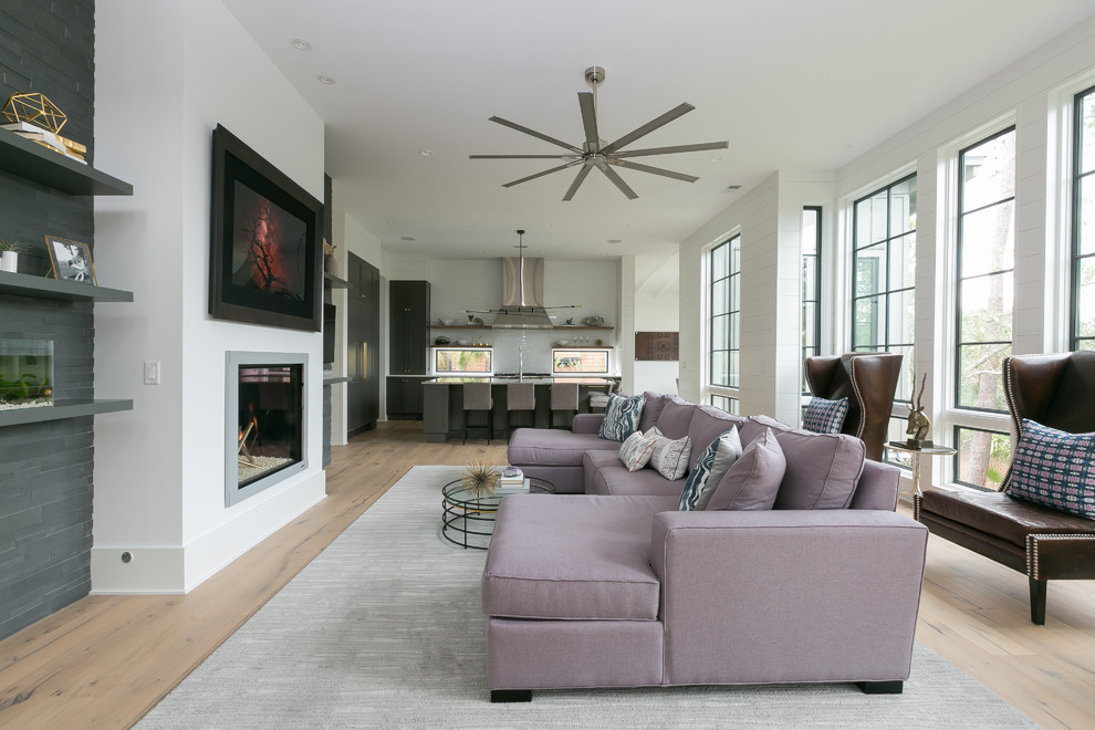 Inspiration for a transitional open concept family room in Charleston with white walls, medium hardwood floors, a standard fireplace, a metal fireplace surround and a wall-mounted tv.