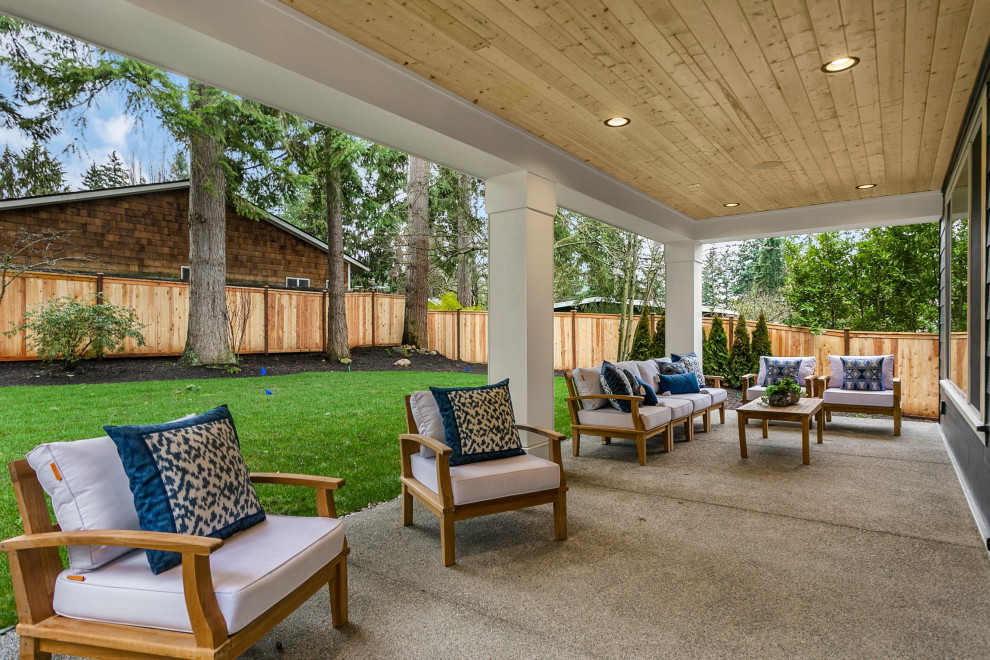 На фото: большой двор на заднем дворе с покрытием из бетонных плит и навесом с