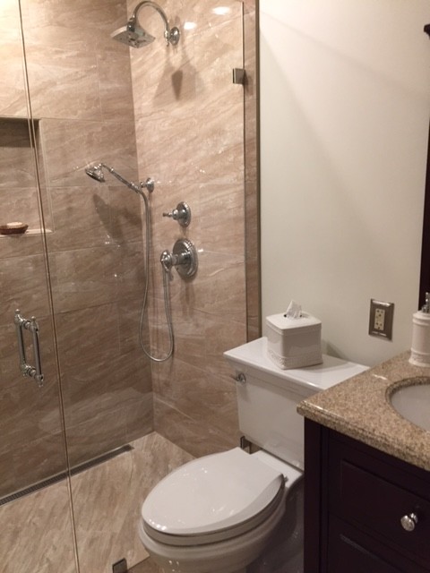 Design ideas for a mid-sized traditional master bathroom in Other with flat-panel cabinets, dark wood cabinets, an alcove shower, a two-piece toilet, beige tile, stone slab, beige walls, porcelain floors, an undermount sink and solid surface benchtops.