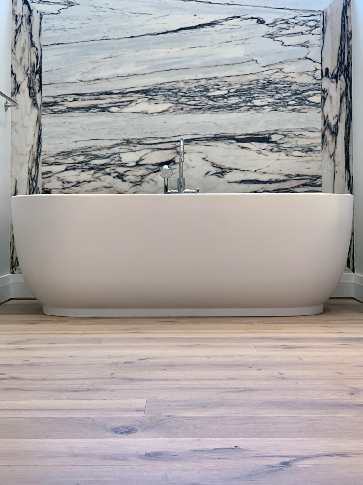 Foto på ett mellanstort funkis flerfärgad en-suite badrum, med luckor med profilerade fronter, vita skåp, ett fristående badkar, svart och vit kakel, marmorkakel, ljust trägolv, ett undermonterad handfat, marmorbänkskiva, brunt golv och dusch med gångjärnsdörr