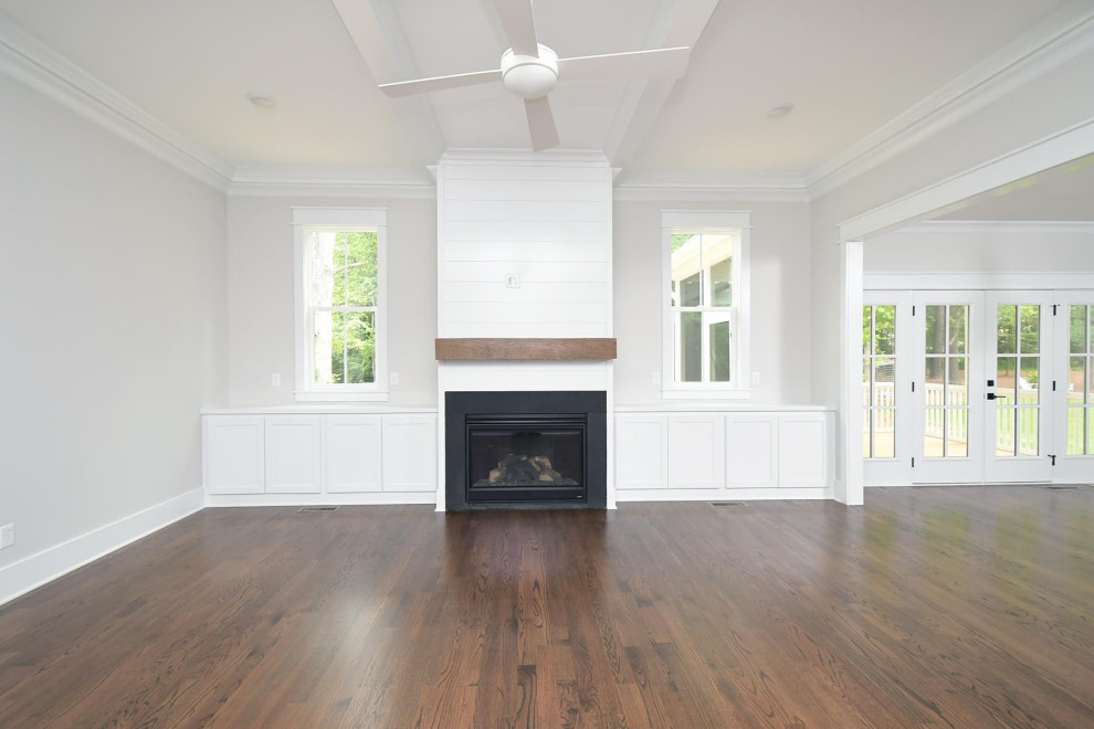 Large traditional open concept family room in Raleigh with white walls, medium hardwood floors, a standard fireplace, brown floor and coffered.