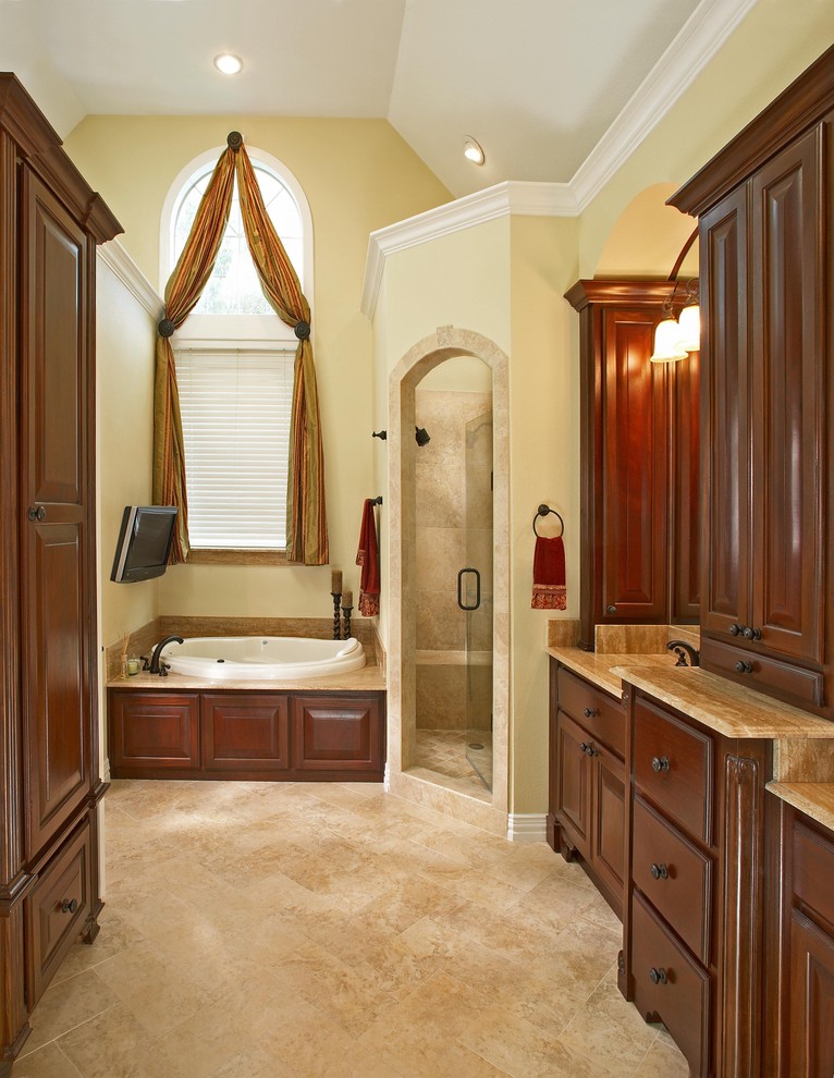 Design ideas for a traditional bathroom in Dallas with raised-panel cabinets, dark wood cabinets, a drop-in tub and beige tile.