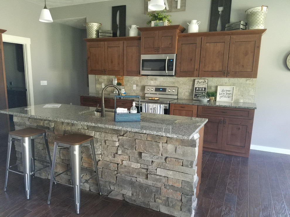 Open concept kitchen - mid-sized rustic single-wall dark wood floor and brown floor open concept kitchen idea with an undermount sink, shaker cabinets, dark wood cabinets, granite countertops, beige backsplash, stone tile backsplash, stainless steel appliances and an island
