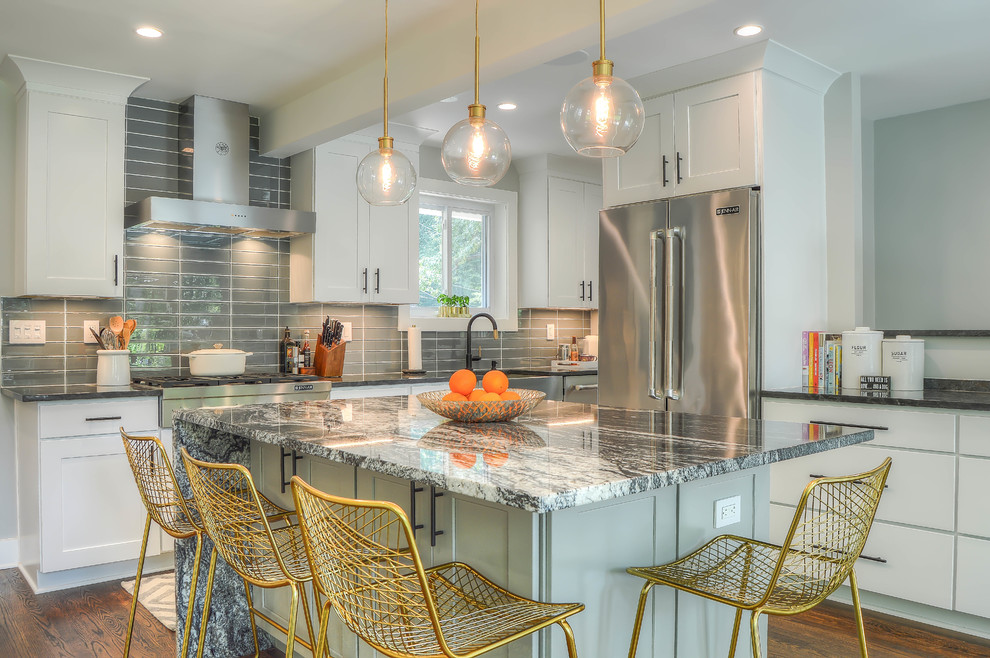 This is an example of a mid-sized transitional kitchen in DC Metro with a farmhouse sink, shaker cabinets, white cabinets, granite benchtops, grey splashback, ceramic splashback, stainless steel appliances, with island, brown floor, grey benchtop and dark hardwood floors.