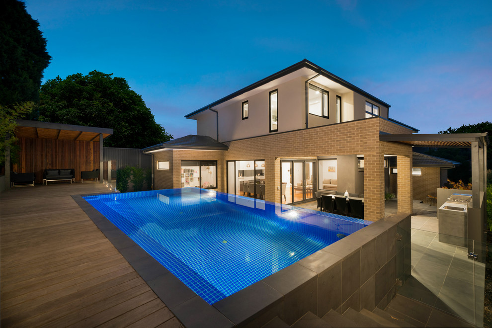 Large contemporary backyard rectangular infinity pool in Melbourne with decking.