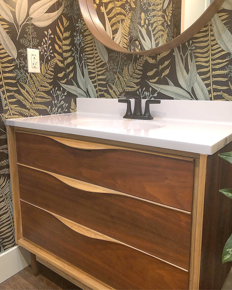 Design ideas for a small tropical powder room in San Diego with multi-coloured walls, engineered quartz benchtops, brown floor, white benchtops, a freestanding vanity, furniture-like cabinets, medium wood cabinets, vinyl floors, an undermount sink and wallpaper.