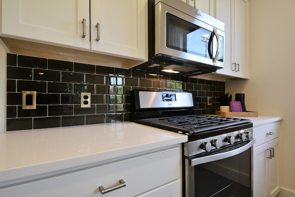 Example of a minimalist galley concrete floor kitchen design in Austin with white cabinets, quartz countertops, black backsplash, subway tile backsplash and stainless steel appliances