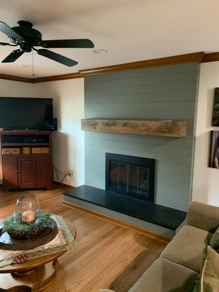 This is an example of a mid-sized country enclosed living room in Columbus with yellow walls, medium hardwood floors, a standard fireplace, brown floor and planked wall panelling.