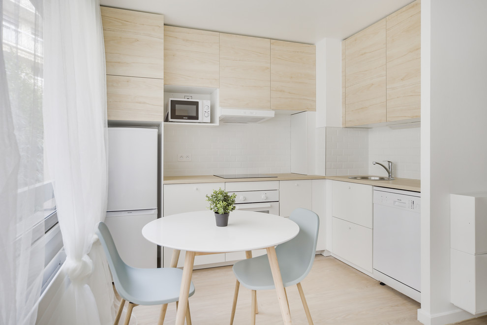 Design ideas for a mid-sized contemporary l-shaped open plan kitchen in Paris with white cabinets, wood benchtops, white splashback, subway tile splashback, white appliances, light hardwood floors, no island, beige floor and brown benchtop.