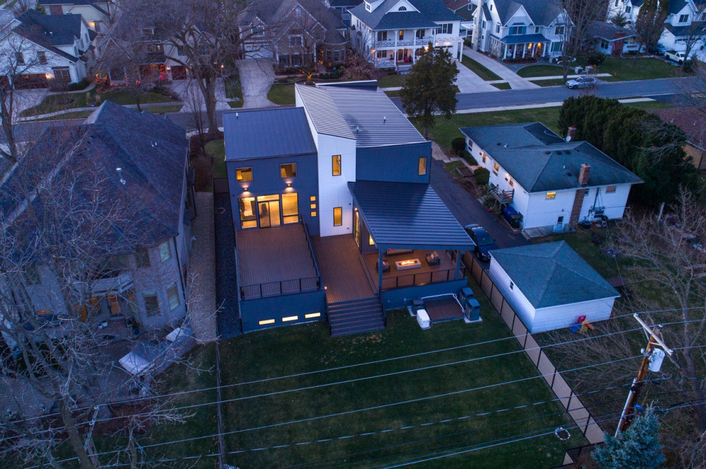 Cette photo montre une grande façade de maison grise moderne à un étage avec un revêtement mixte, un toit en appentis et un toit en métal.
