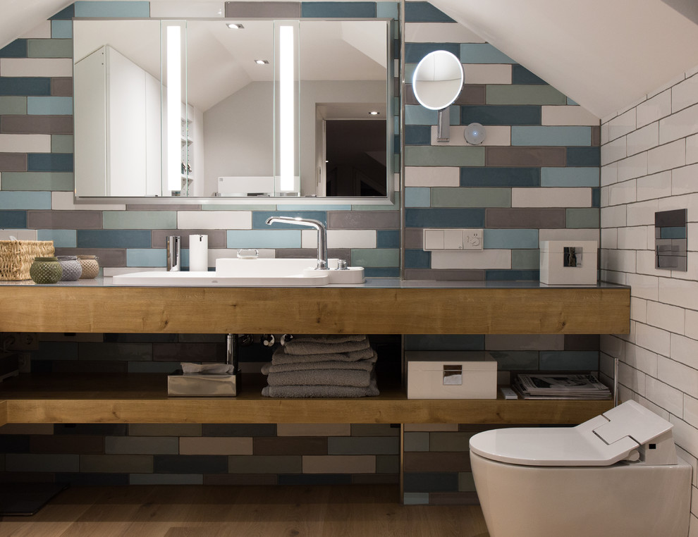 Inspiration for a large contemporary 3/4 bathroom in Frankfurt with open cabinets, white cabinets, a curbless shower, a two-piece toilet, multi-coloured tile, ceramic tile, multi-coloured walls, painted wood floors, a vessel sink, glass benchtops, brown floor and a hinged shower door.