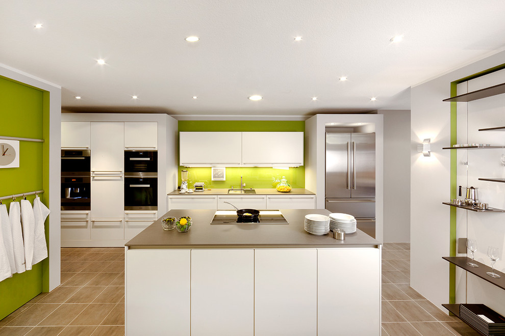 Inspiration for a large contemporary galley open plan kitchen in Dortmund with an integrated sink, flat-panel cabinets, white cabinets, with island, wood benchtops, green splashback, stainless steel appliances and concrete floors.
