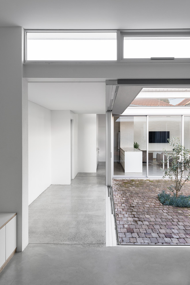 Large contemporary hallway in Sydney with white walls, concrete floors and grey floor.