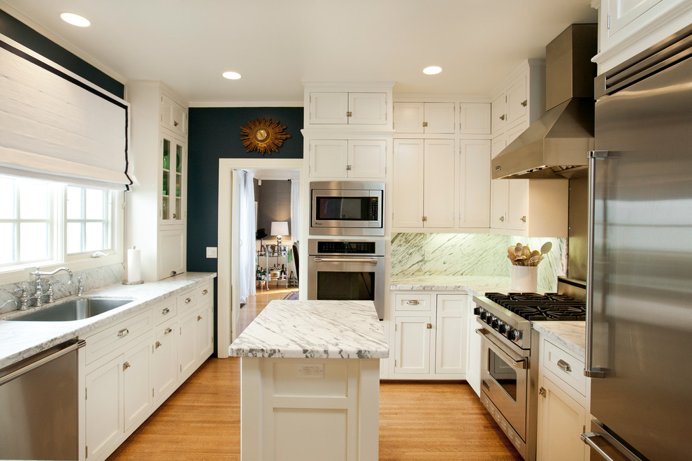 Transitional u-shaped separate kitchen in Los Angeles with an undermount sink, shaker cabinets, white cabinets, marble benchtops, white splashback, stone tile splashback and stainless steel appliances.