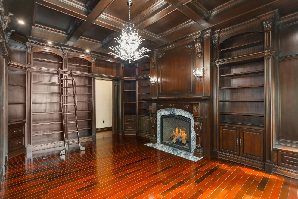 Example of a large classic medium tone wood floor, multicolored floor, coffered ceiling and wood wall home office library design in New York with brown walls, a hanging fireplace and a wood fireplace surround