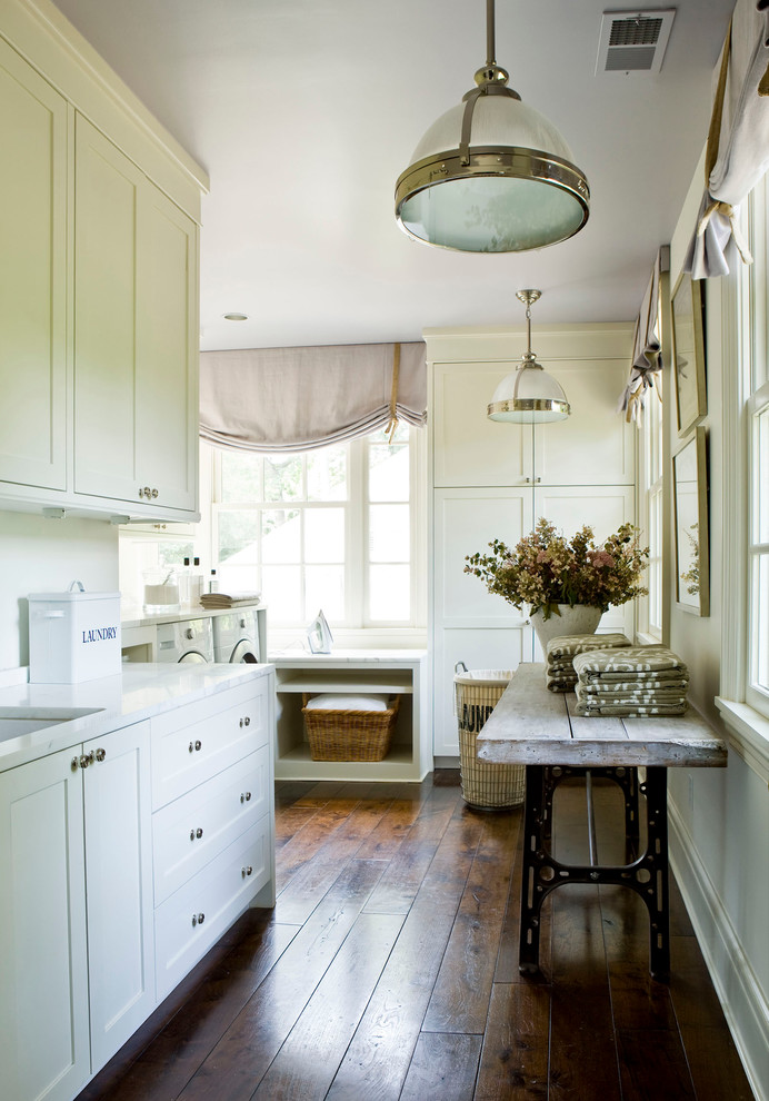 This is an example of a large country dedicated laundry room in Atlanta with an undermount sink, shaker cabinets, white cabinets, white walls and dark hardwood floors.
