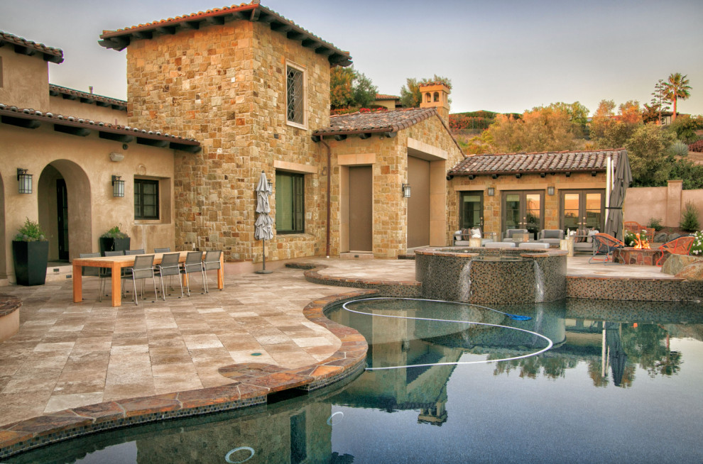 Large mediterranean backyard full sun xeriscape in San Diego with a fire feature and natural stone pavers.