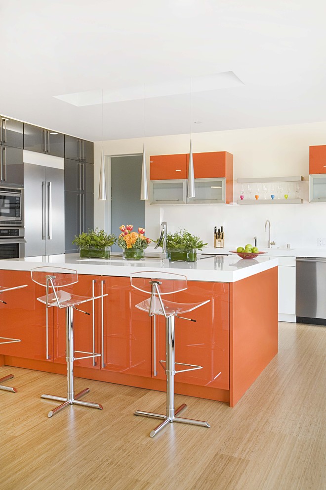 This is an example of a contemporary kitchen in San Francisco with stainless steel appliances, flat-panel cabinets, orange cabinets, quartz benchtops and bamboo floors.