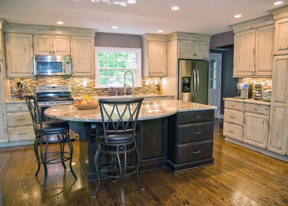 This is an example of a traditional l-shaped eat-in kitchen in Louisville with an undermount sink, raised-panel cabinets, distressed cabinets, granite benchtops and stainless steel appliances.