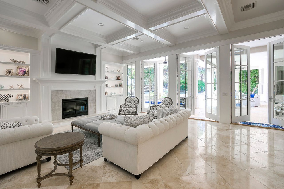 Example of a large classic open concept travertine floor, coffered ceiling and wainscoting family room design in Phoenix with beige walls, a standard fireplace, a wood fireplace surround and a wall-mounted tv