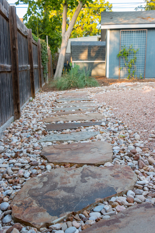 Design ideas for a mid-sized contemporary side yard partial sun xeriscape for summer in Austin with a wood fence, with path and natural stone pavers.