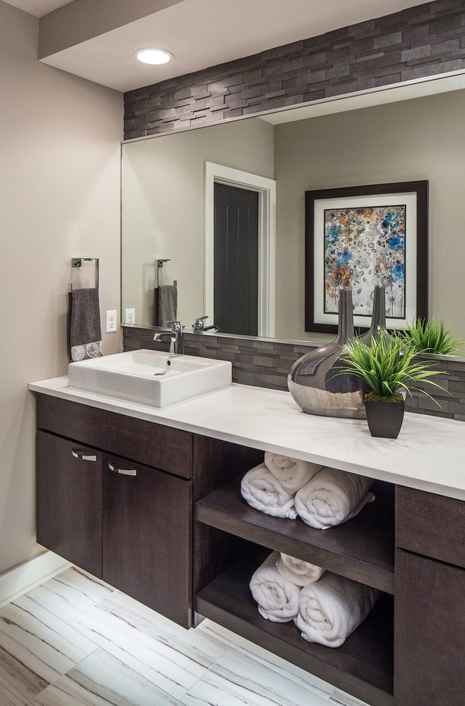 Design ideas for a contemporary master bathroom in Omaha with flat-panel cabinets, dark wood cabinets, a freestanding tub, brown tile, grey walls, a vessel sink and white benchtops.