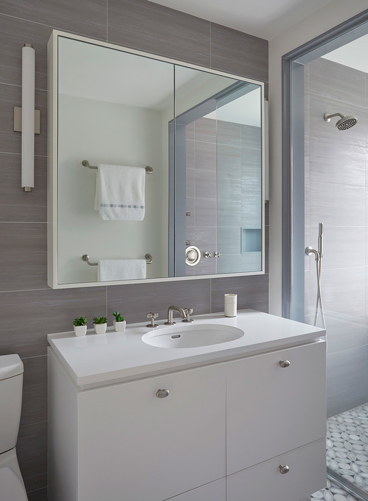 Photo of a mid-sized transitional master wet room bathroom in New York with flat-panel cabinets, white cabinets, a freestanding tub, gray tile, ceramic tile, grey walls, marble floors, an undermount sink, grey floor and an open shower.