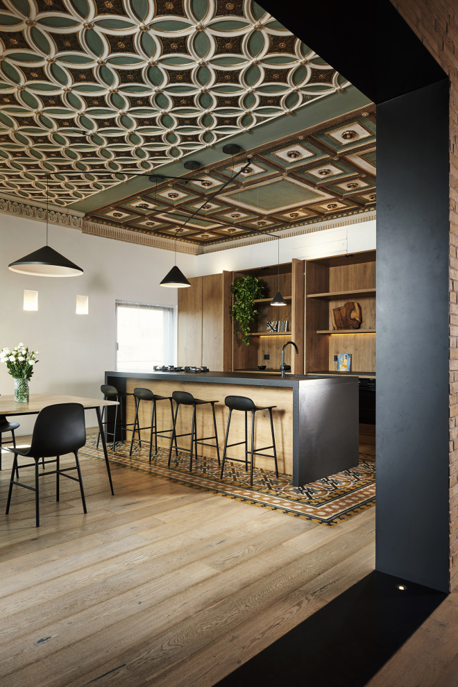 Foto di un cucina con isola centrale design con parquet chiaro, top nero e soffitto a cassettoni