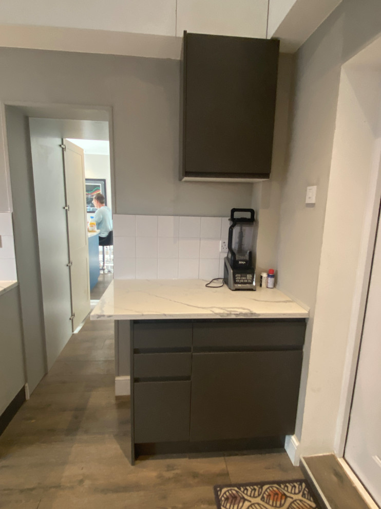 Inspiration for a large contemporary galley utility room in London with a drop-in sink, flat-panel cabinets, grey cabinets, quartzite benchtops, white splashback, porcelain splashback, beige walls, laminate floors, a side-by-side washer and dryer, grey floor and multi-coloured benchtop.
