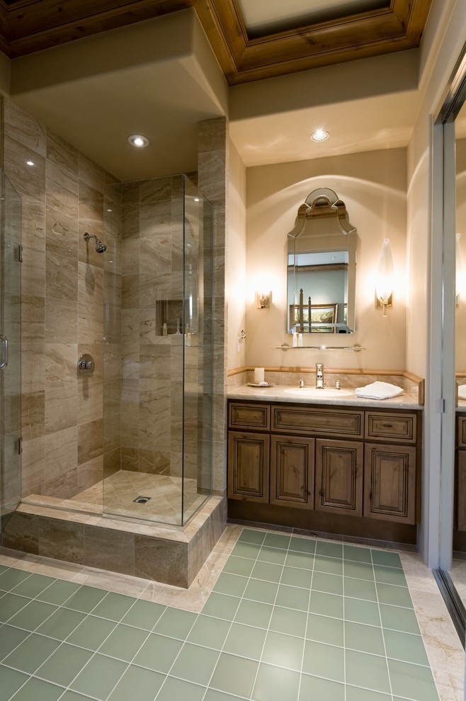This is an example of a large traditional master bathroom in Toronto with raised-panel cabinets, medium wood cabinets, a corner shower, beige walls, porcelain floors, an undermount sink and limestone benchtops.