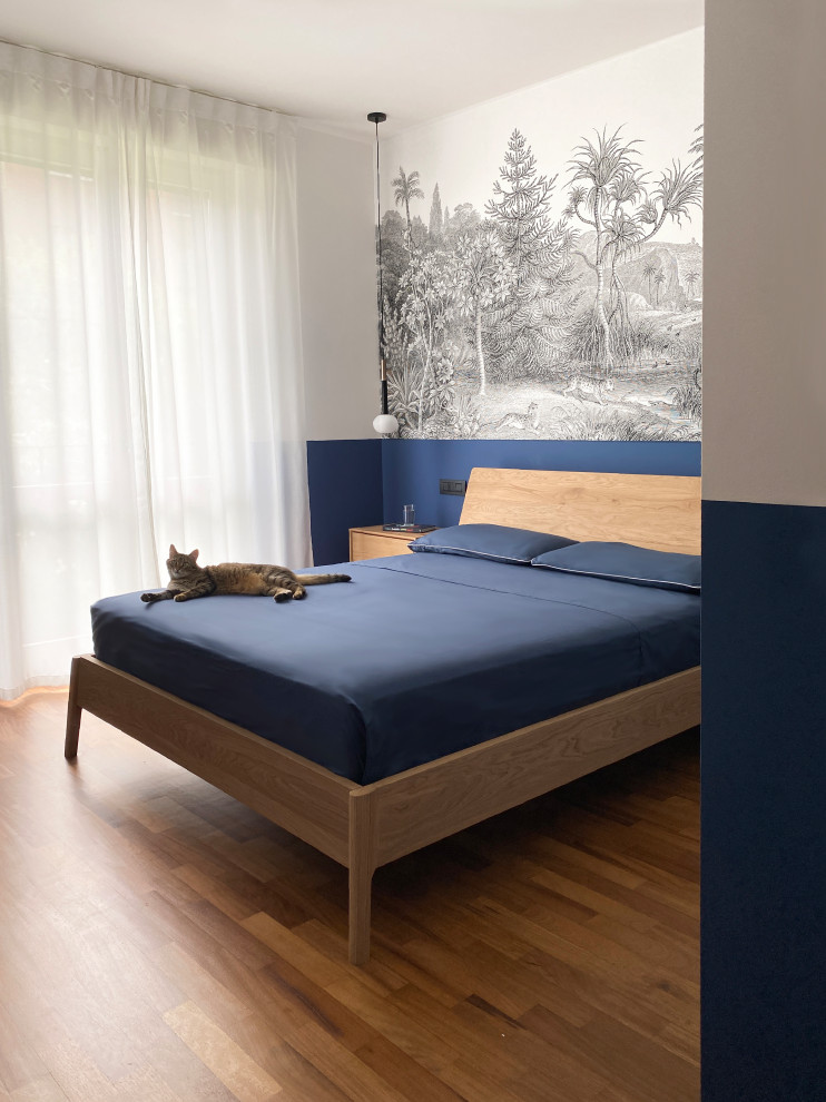 他の地域にある広いおしゃれな寝室 (青い壁、濃色無垢フローリング、暖炉なし、ベージュの床、壁紙) のインテリア