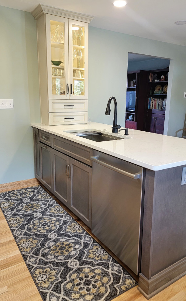 Inspiration for a mid-sized transitional l-shaped medium tone wood floor and yellow floor eat-in kitchen remodel with an undermount sink, flat-panel cabinets, gray cabinets, quartz countertops, white backsplash, ceramic backsplash, stainless steel appliances, an island and white countertops