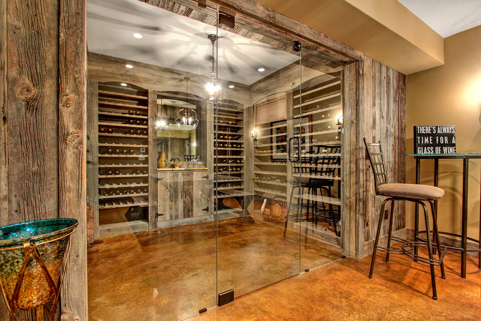 Mid-sized country wine cellar in Other with storage racks and concrete floors.