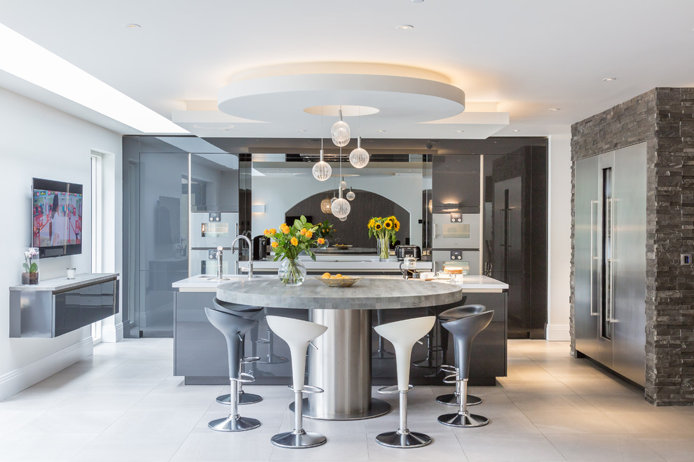 This is an example of a large contemporary eat-in kitchen in Manchester with a drop-in sink, grey cabinets, granite benchtops, metallic splashback, glass sheet splashback, stainless steel appliances, porcelain floors, multiple islands, grey floor and white benchtop.