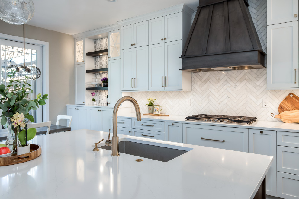 Inspiration for a large transitional galley medium tone wood floor and brown floor open concept kitchen remodel in Denver with an undermount sink, shaker cabinets, white cabinets, quartz countertops, beige backsplash, marble backsplash, stainless steel appliances, an island and white countertops