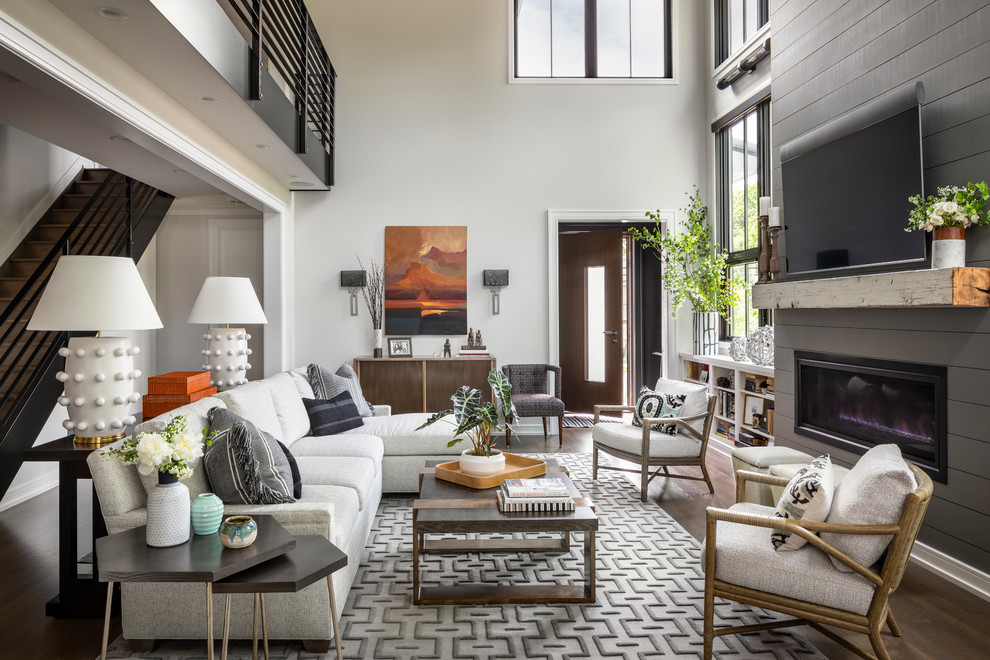 Design ideas for a transitional family room in New York with white walls, dark hardwood floors, a standard fireplace, a wood fireplace surround and a wall-mounted tv.