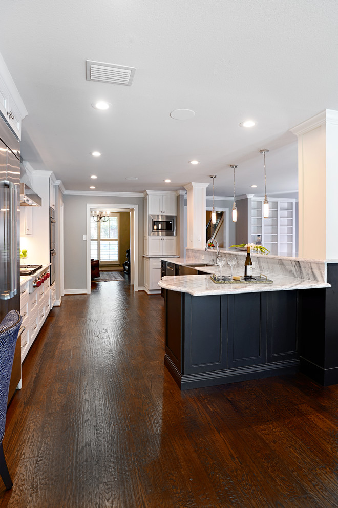 Inspiration for a large transitional single-wall dark wood floor eat-in kitchen remodel in Dallas with a farmhouse sink, shaker cabinets, white cabinets, marble countertops, beige backsplash, glass tile backsplash, stainless steel appliances and an island