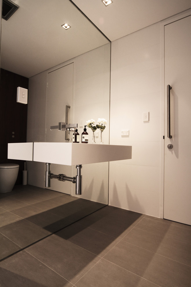 This is an example of a contemporary powder room in Perth with a wall-mount sink, a wall-mount toilet, gray tile and porcelain floors.