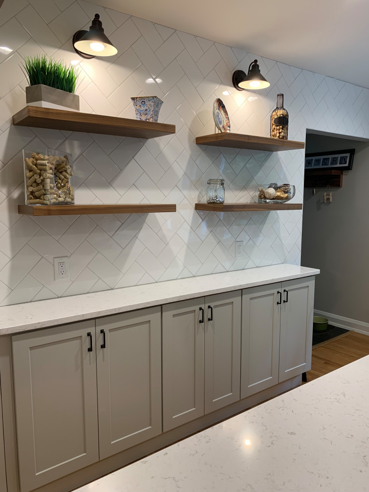 Eat-in kitchen - mid-sized transitional l-shaped medium tone wood floor eat-in kitchen idea in Baltimore with a farmhouse sink, shaker cabinets, gray cabinets, quartz countertops, white backsplash, subway tile backsplash, stainless steel appliances, an island and white countertops