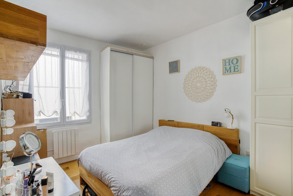 Inspiration pour une chambre parentale design de taille moyenne avec un mur blanc, parquet clair et un sol marron.