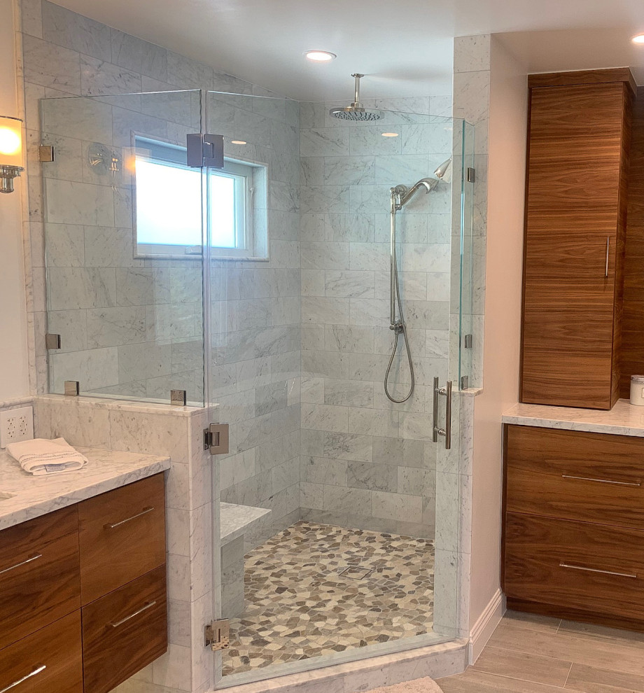 Photo of a large contemporary ensuite bathroom in Los Angeles with flat-panel cabinets, medium wood cabinets, a freestanding bath, an alcove shower, a one-piece toilet, multi-coloured tiles, marble tiles, white walls, porcelain flooring, a submerged sink, marble worktops, brown floors, a hinged door, multi-coloured worktops, a shower bench, double sinks and a floating vanity unit.