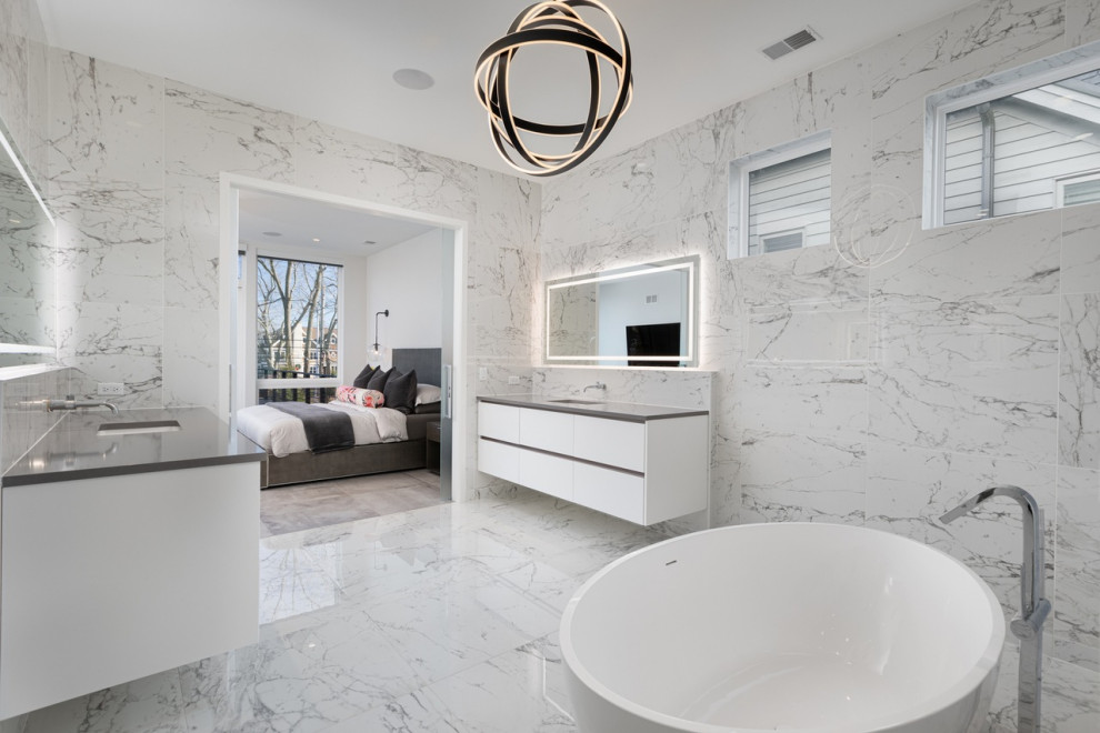 Modern inredning av ett stort grå grått en-suite badrum, med släta luckor, vita skåp, ett japanskt badkar, en dubbeldusch, en toalettstol med hel cisternkåpa, grå kakel, marmorkakel, grå väggar, marmorgolv, ett undermonterad handfat, marmorbänkskiva, grått golv och dusch med gångjärnsdörr