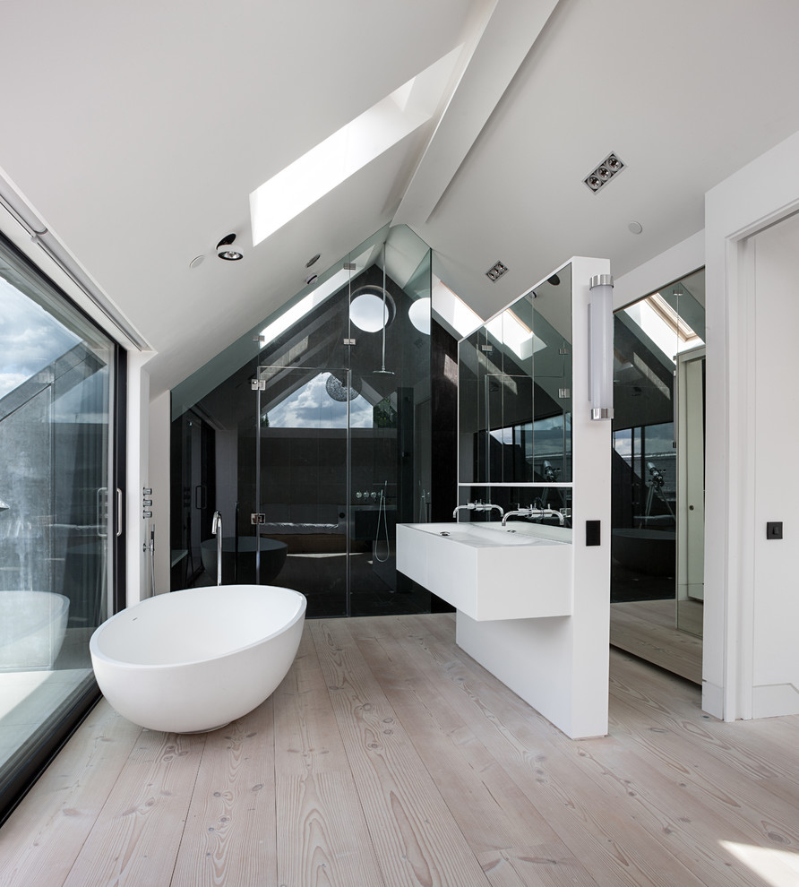 This is an example of a mid-sized contemporary bathroom in London with a trough sink, white cabinets, a freestanding tub, an alcove shower, white walls and light hardwood floors.
